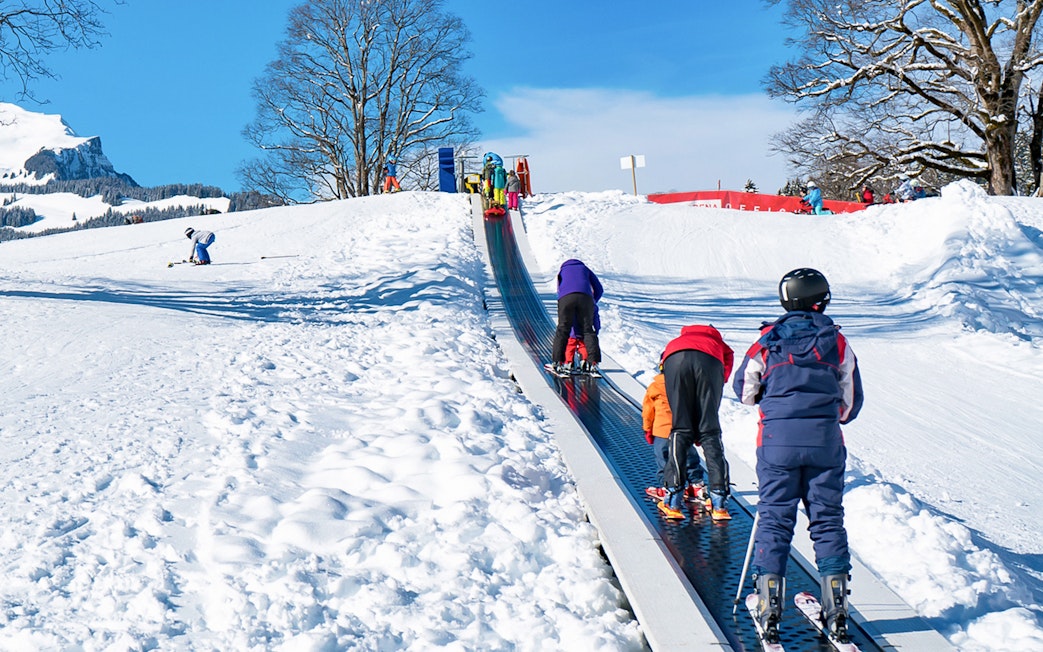 Children on a ski conveyor belt in Grindelwald during a beginner ski lesson.