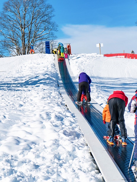 Children on a ski conveyor belt in Grindelwald during a beginner ski lesson.