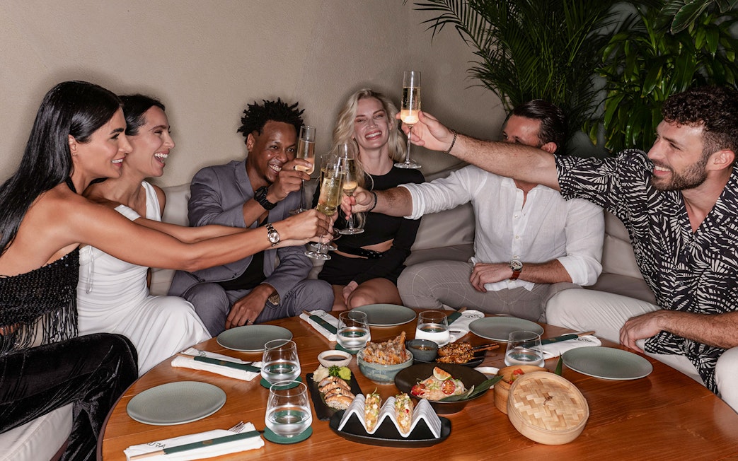 Group enjoying a meal and drinks at Aura Sky Pool.