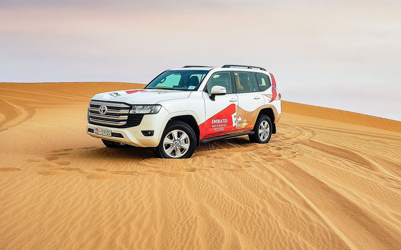 SUV on sand dunes during Abu Dhabi desert safari tour.