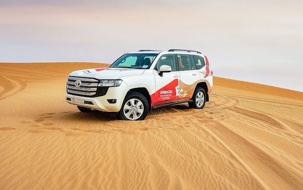 SUV on sand dunes during Abu Dhabi desert safari tour.