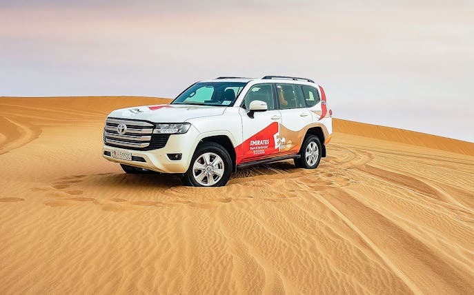 SUV on sand dunes during Abu Dhabi desert safari tour.