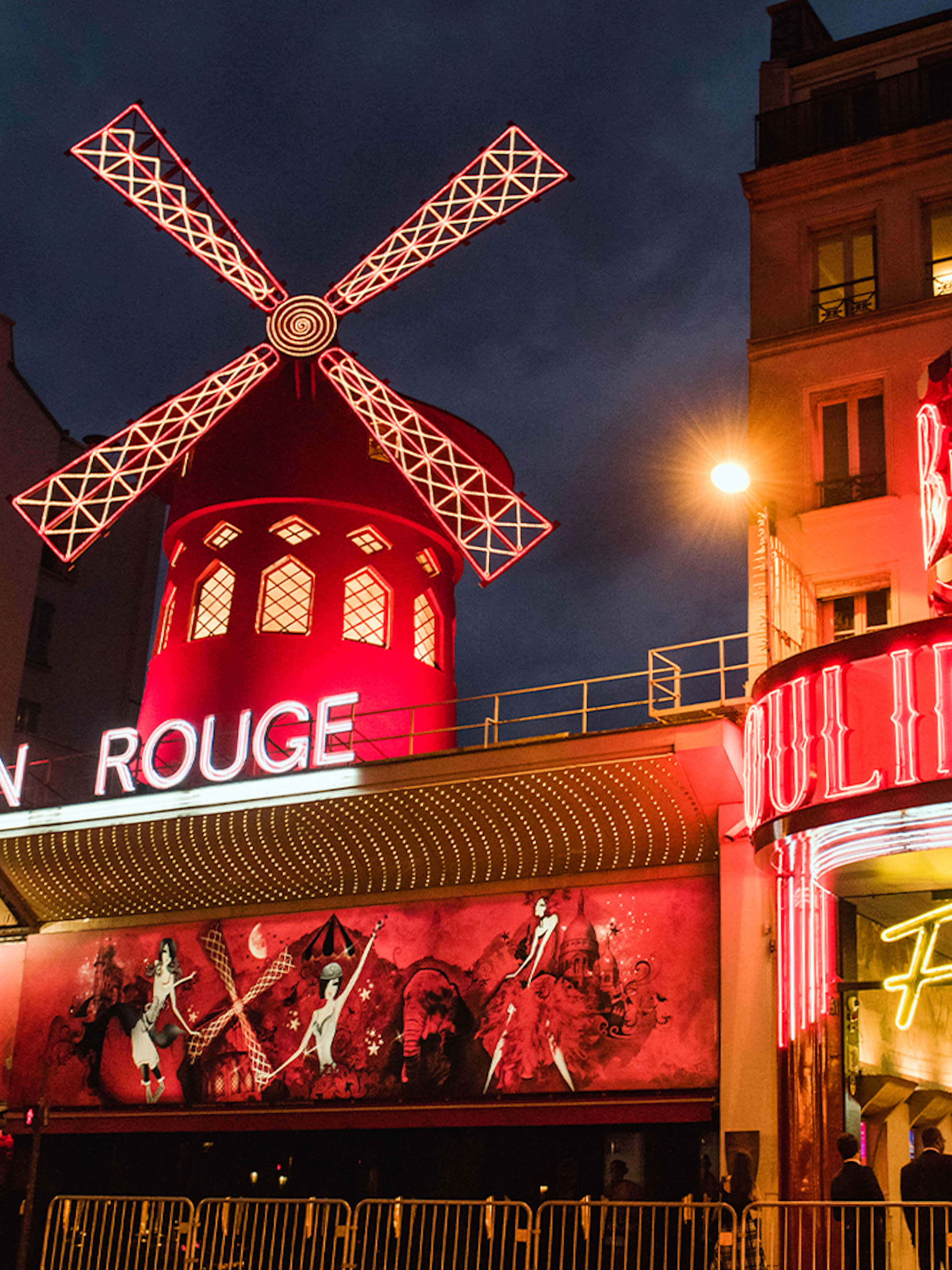Moulin Rouge in Paris illuminated at night with iconic red windmill.