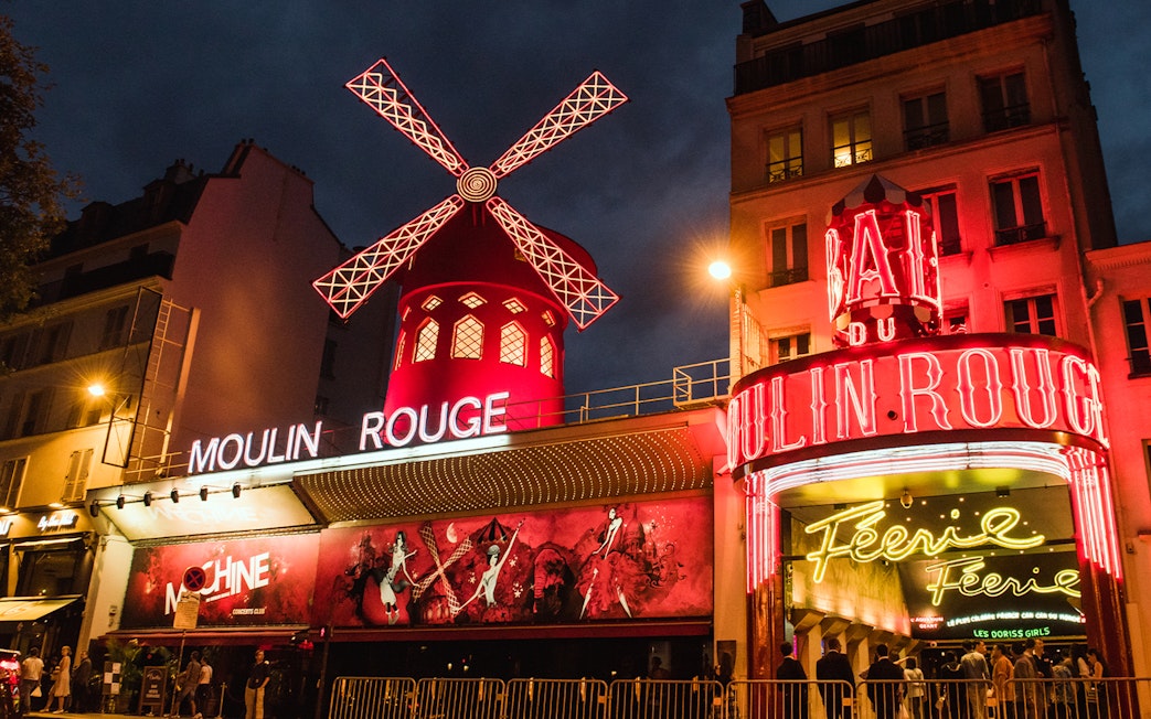 Moulin Rouge in Paris illuminated at night with iconic red windmill.
