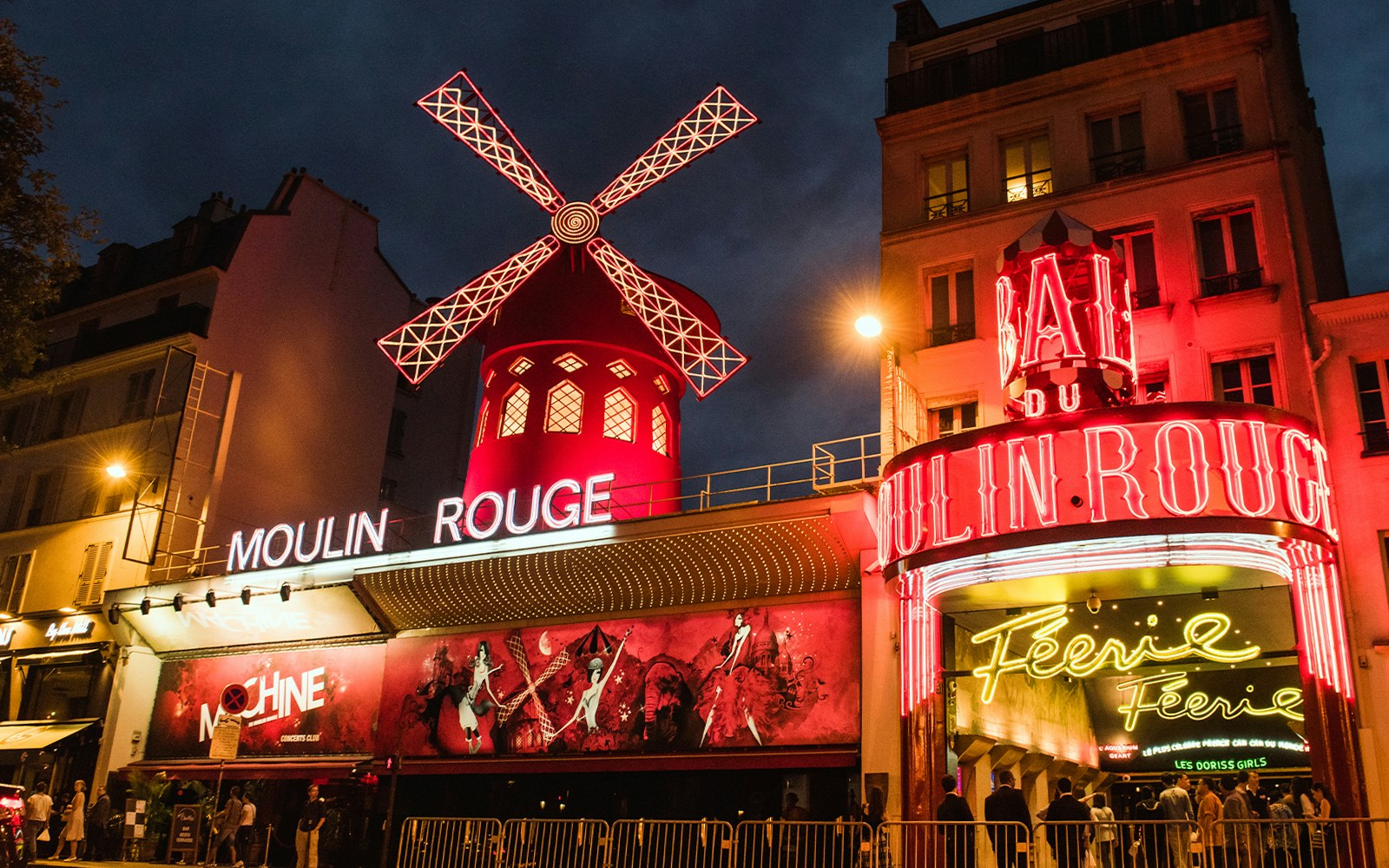 Moulin Rouge Paris illuminated exterior at night with iconic windmill.