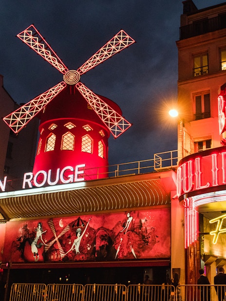 Moulin Rouge in Paris illuminated at night with iconic red windmill.