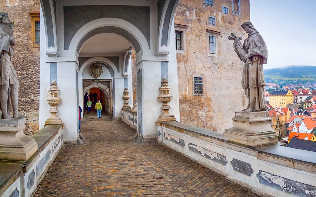 Cesky Krumlov Castle bridge with statues and archway, Czech Republic.