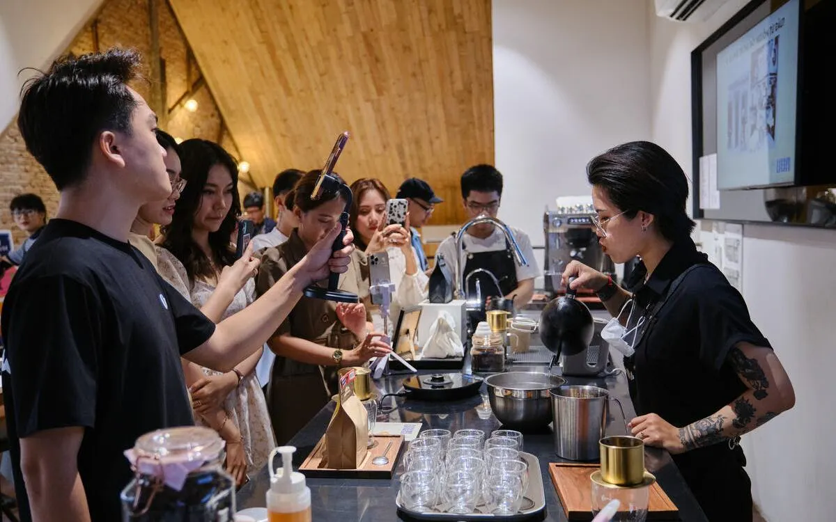 Barista demonstrating Vietnamese egg coffee preparation to a group in a Hanoi café.