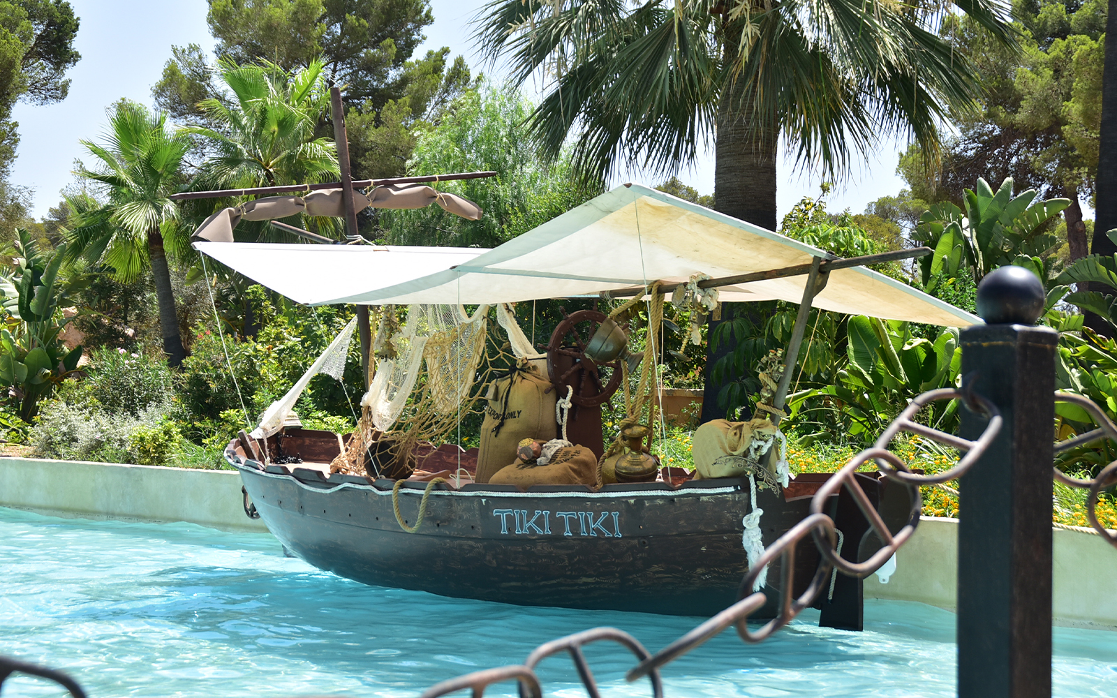 Tiki-themed boat on water at Aqualand El Arenal surrounded by tropical plants.