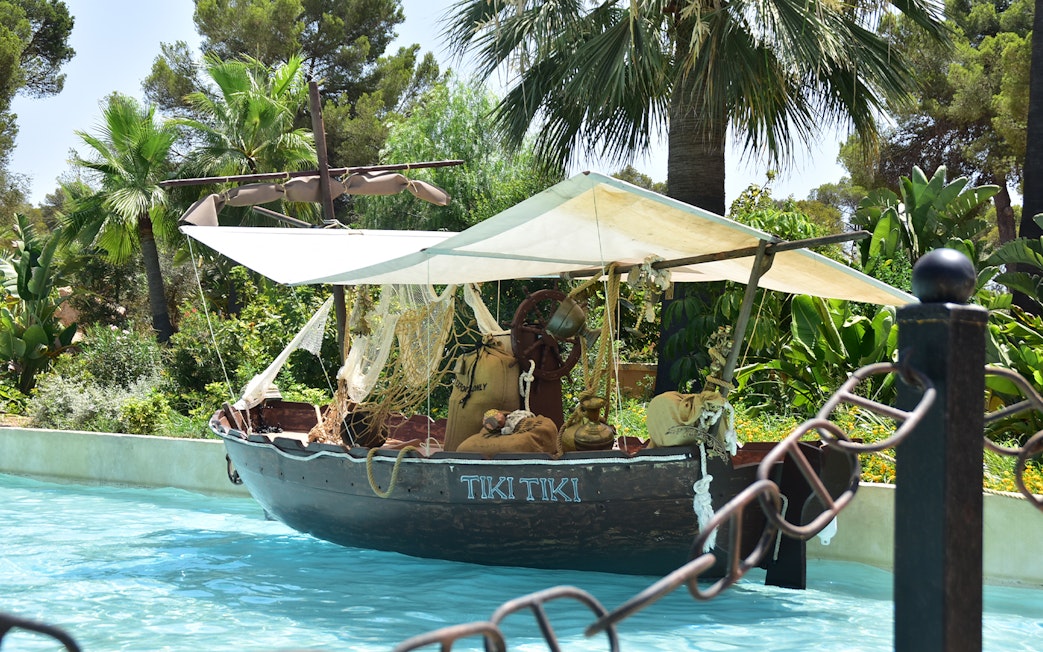 Tiki-themed boat on water at Aqualand El Arenal surrounded by tropical plants.