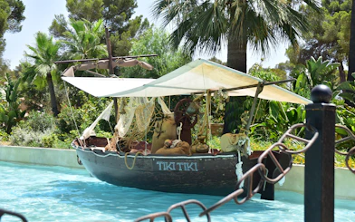 Tiki-themed boat on water at Aqualand El Arenal surrounded by tropical plants.