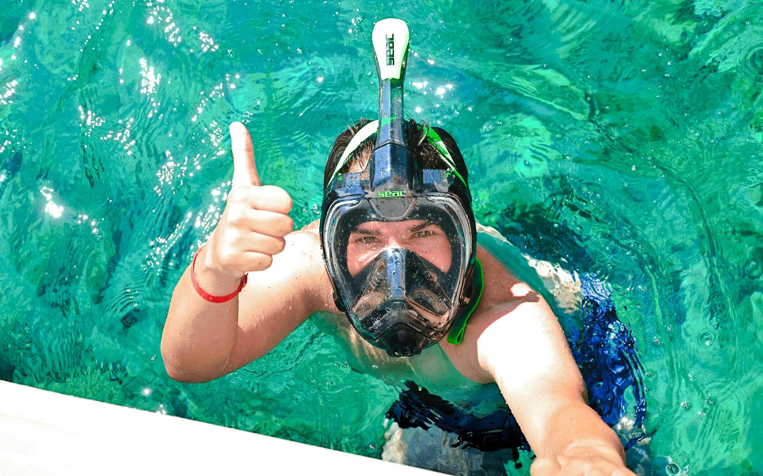 Snorkeler giving thumbs up in clear waters during Chrissi Island catamaran cruise.