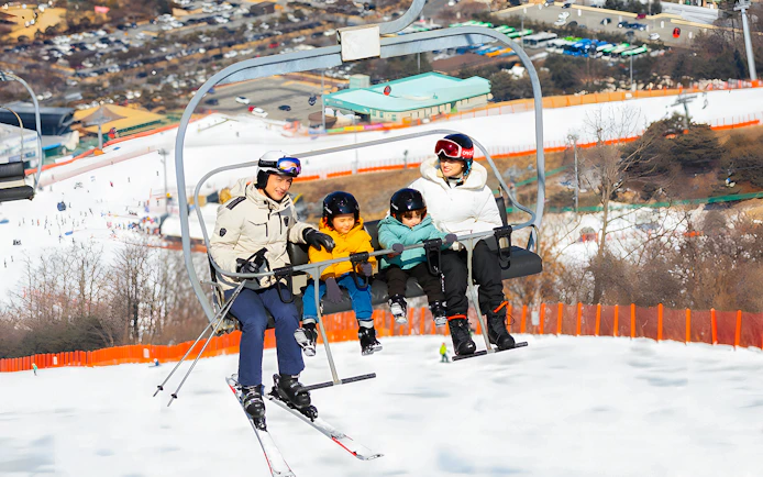Family on ski lift at Vivaldi Park Snowy Land, Seoul day tour.