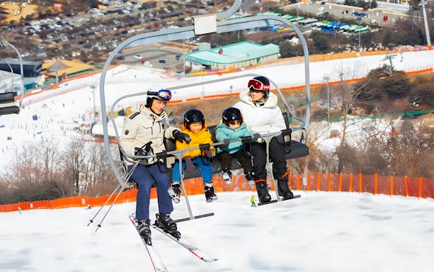 Family on ski lift at Vivaldi Park Snowy Land, Seoul day tour.