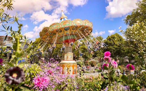 Carousel swing ride at Tivoli Gardens, Copenhagen surrounded by colorful flowers.