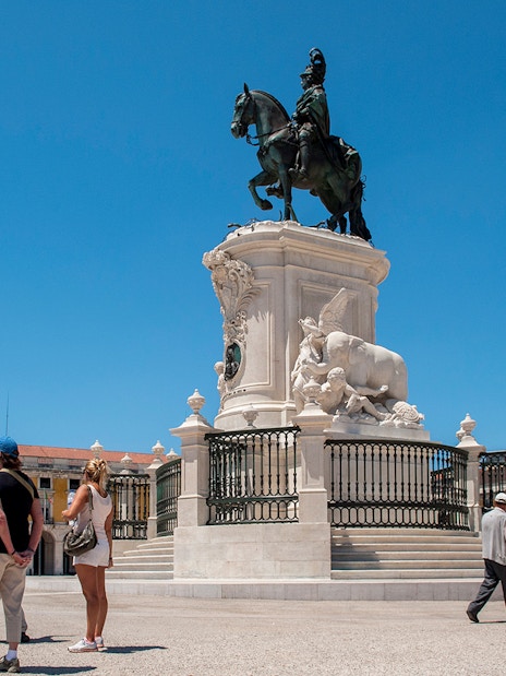 Tourists at Praça do Comércio in Lisbon with equestrian statue of King José I.