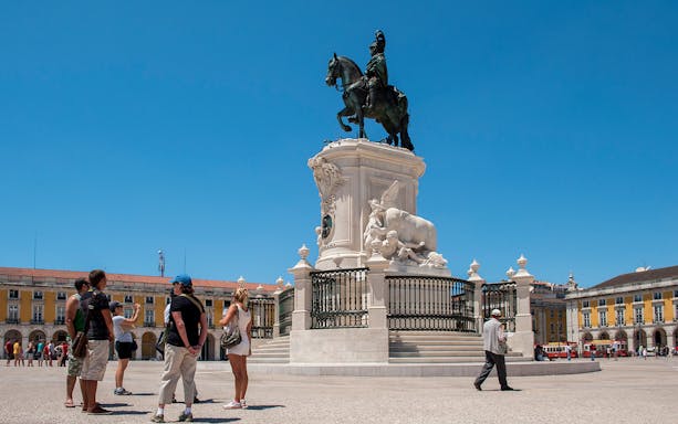 Tourists at Praça do Comércio in Lisbon with equestrian statue of King José I.