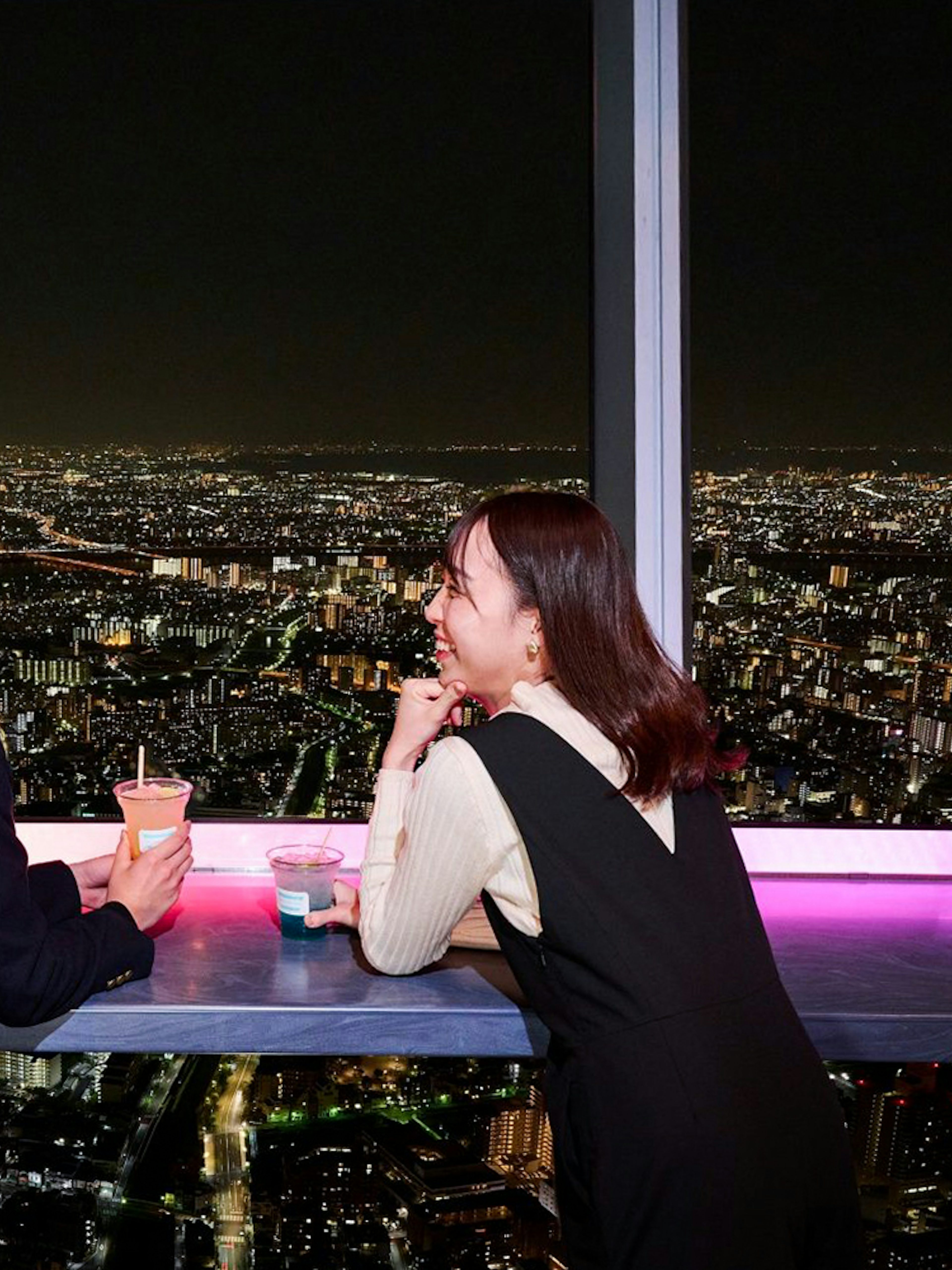 Tourists enjoying drinks with a night view of Tokyo from the Tembo Deck.