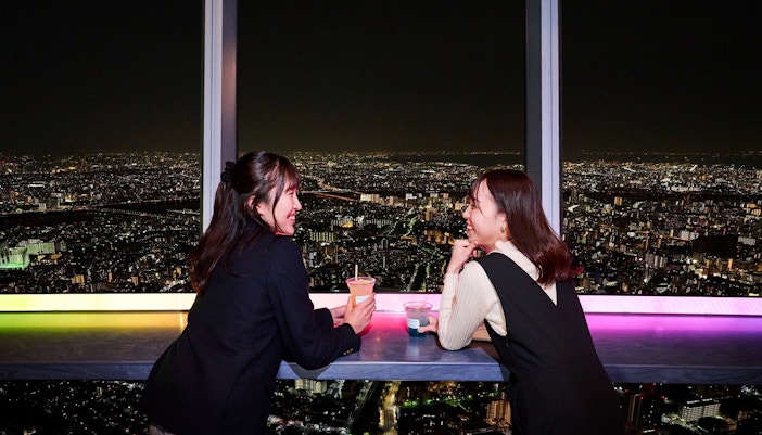 Tourists enjoying drinks at Tokyo's Tembo Deck with city skyline views.