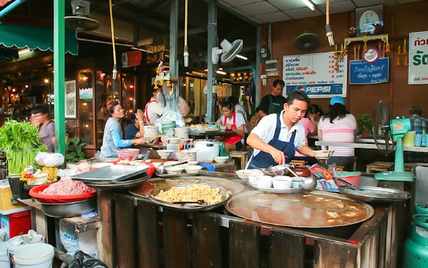 Street food vendor serving dishes at a bustling local market in Kuala Lumpur.