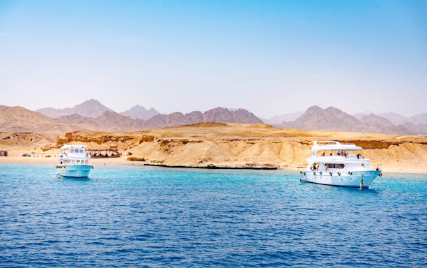 Boat cruising the Red Sea near White Island, Sharm El-Sheikh, with tourists enjoying the scenic view.