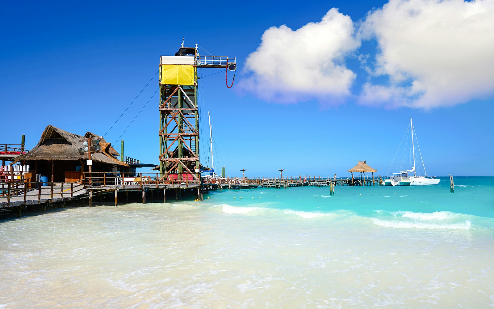 Playa Tortugas beach with pier and sailboat in Cancun, Mexico.