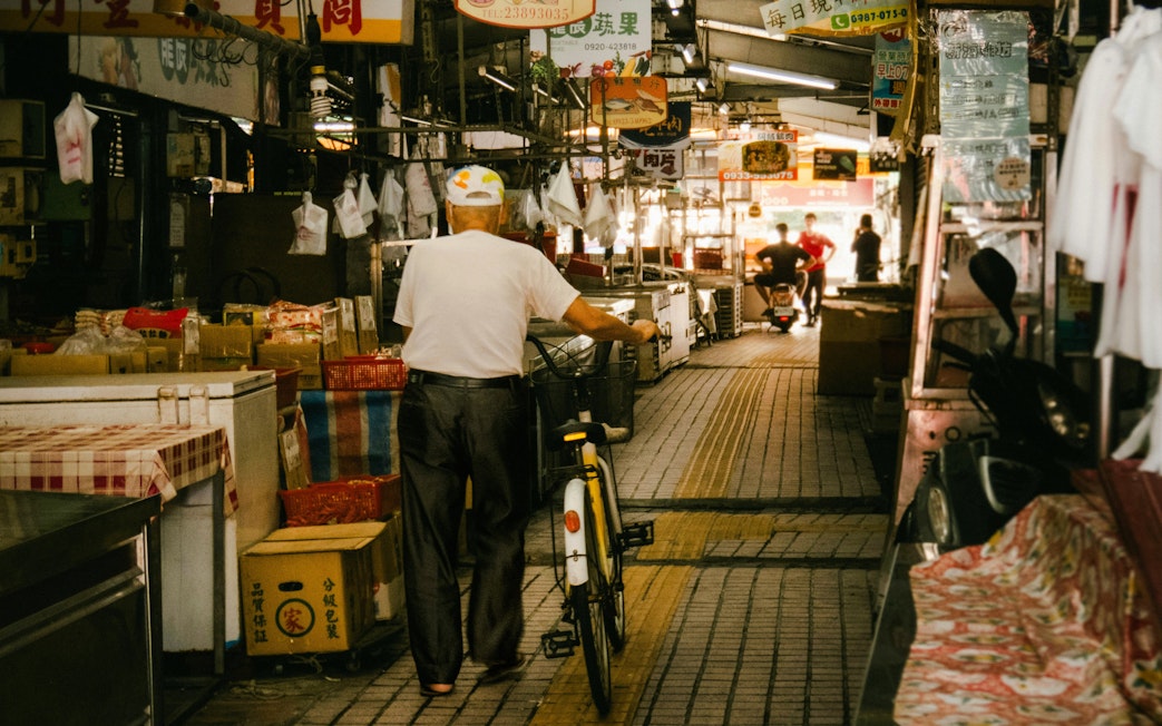 Man with bicycle walking through Tsukiji Outer Market in Tokyo, Japan.