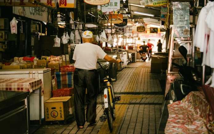Man with bicycle walking through Tsukiji Outer Market in Tokyo, Japan.