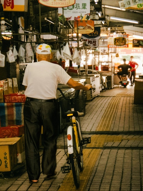 Man with bicycle walking through Tsukiji Outer Market in Tokyo, Japan.