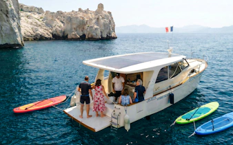 Boat tour at Frioul Archipelago with passengers boarding near rocky coastline.