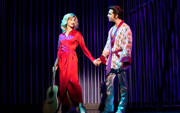 Performers on stage in "A Beautiful Noise: The Neil Diamond Musical" holding hands.