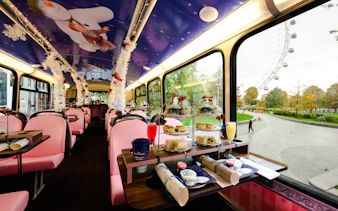 Afternoon tea setup inside a decorated bus with The Snowman™ theme, overlooking the London Eye.