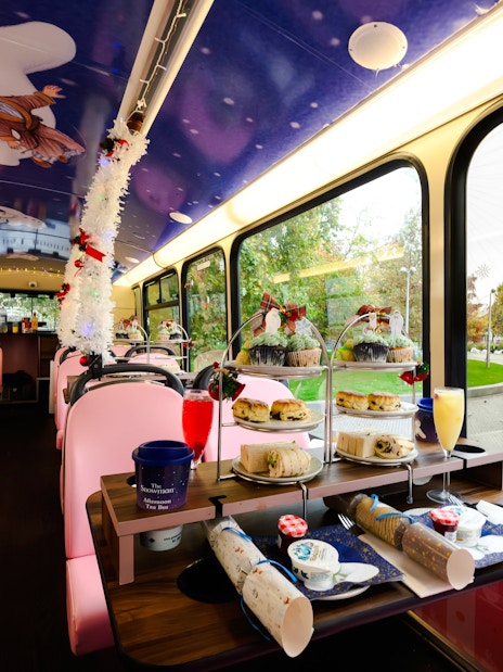 Afternoon tea setup inside a decorated bus with The Snowman™ theme, overlooking the London Eye.