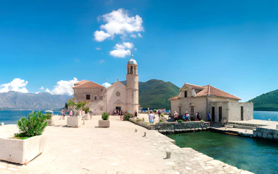 Our Lady of the Rocks church on an islet near Perast, with tourists exploring, Kotor Bay.