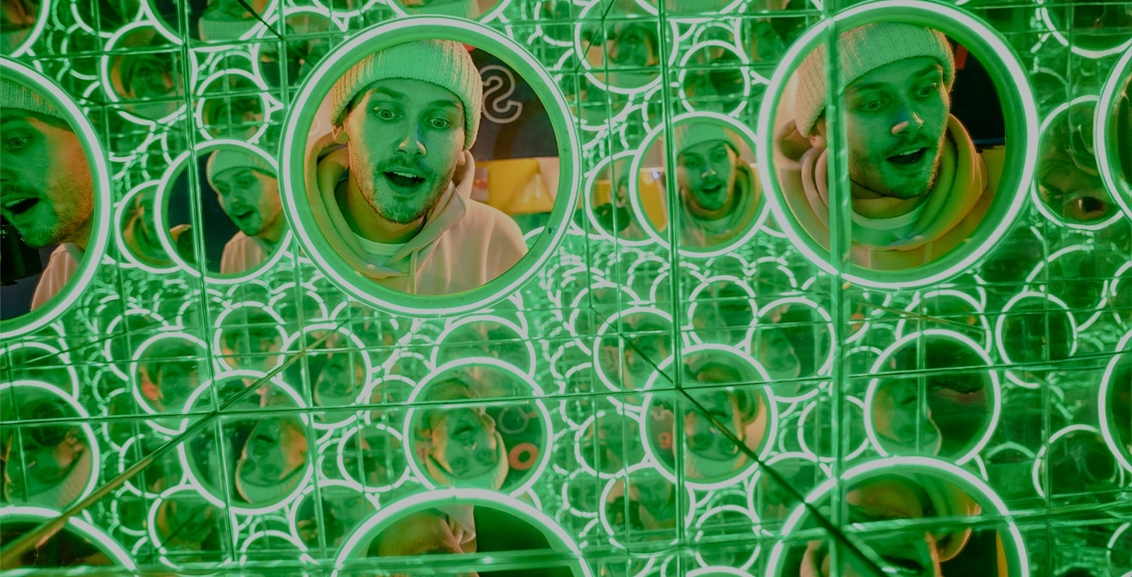 Man's face reflected in multiple green-lit mirrors at World of Illusions, Dublin.