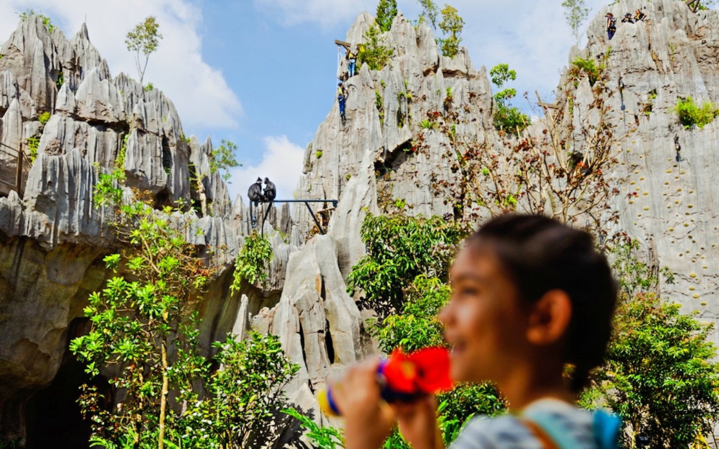 Rock formations and lush greenery in The Karsts, Rainforest Wild Asia, with people exploring.