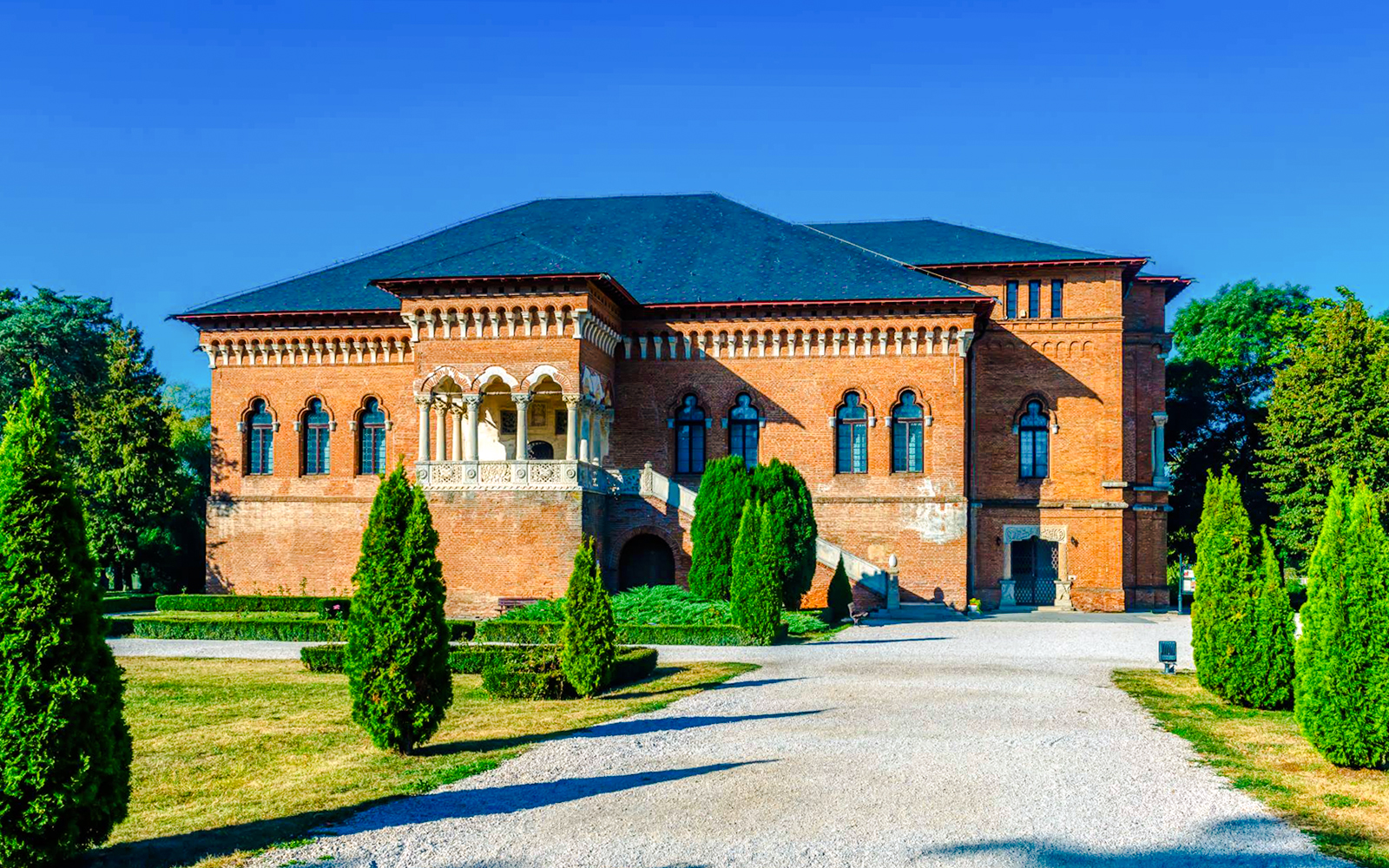 Mogosoaia Palace in Romania with its red brick facade and manicured gardens.