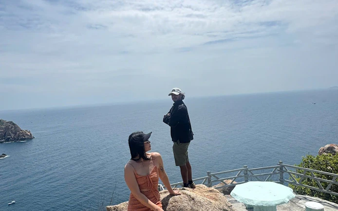 People enjoying ocean view from a rocky viewpoint in Nha Trang, Vietnam.