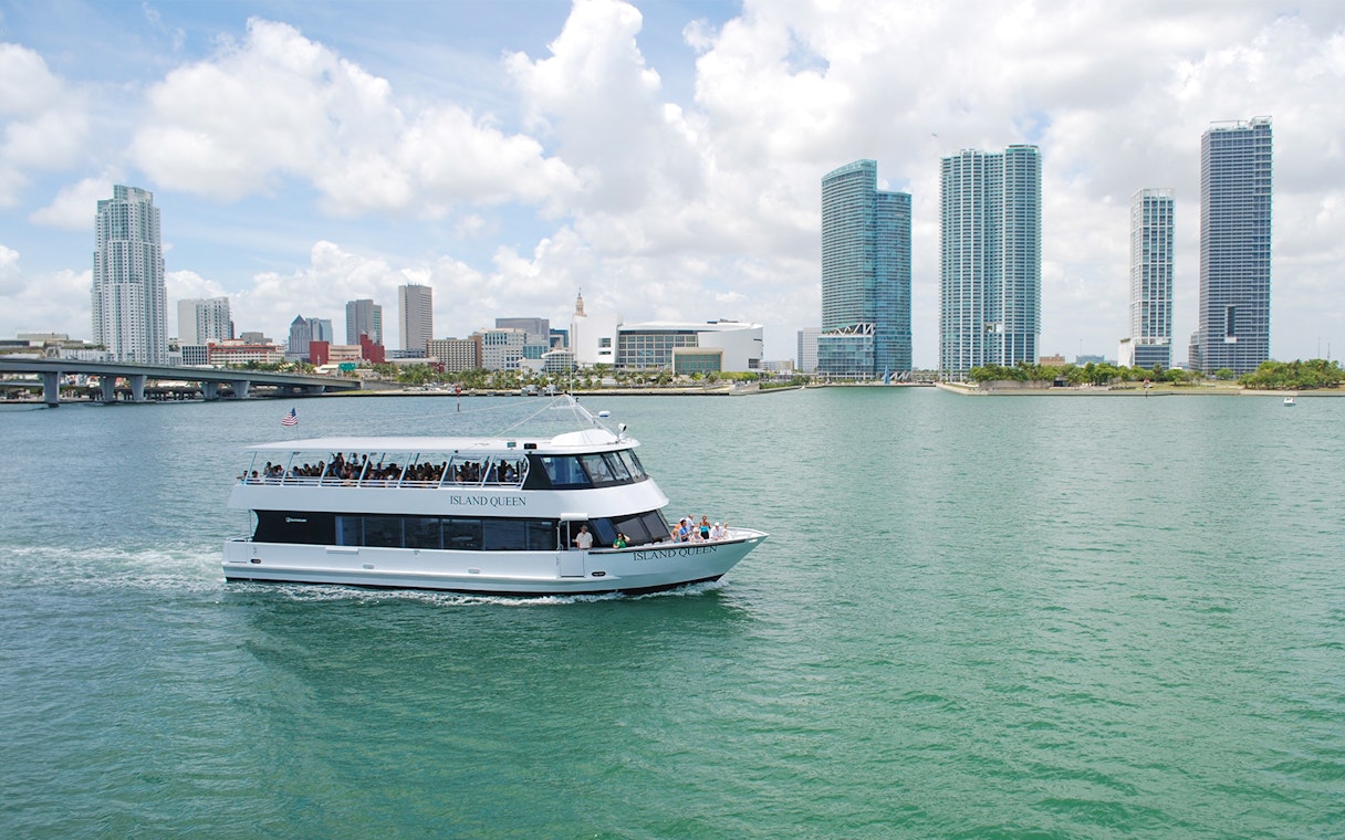 Sightseeing cruise boat on Miami's Biscayne Bay with city skyline in the background.