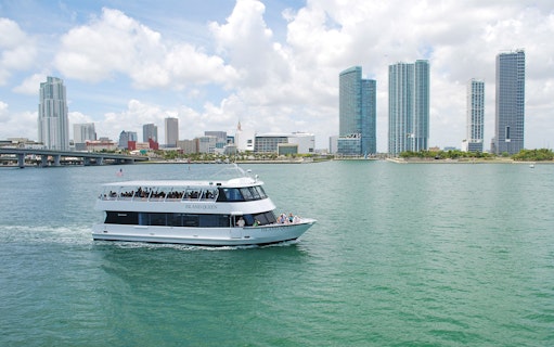 Sightseeing cruise boat on Miami's Biscayne Bay with city skyline in the background.
