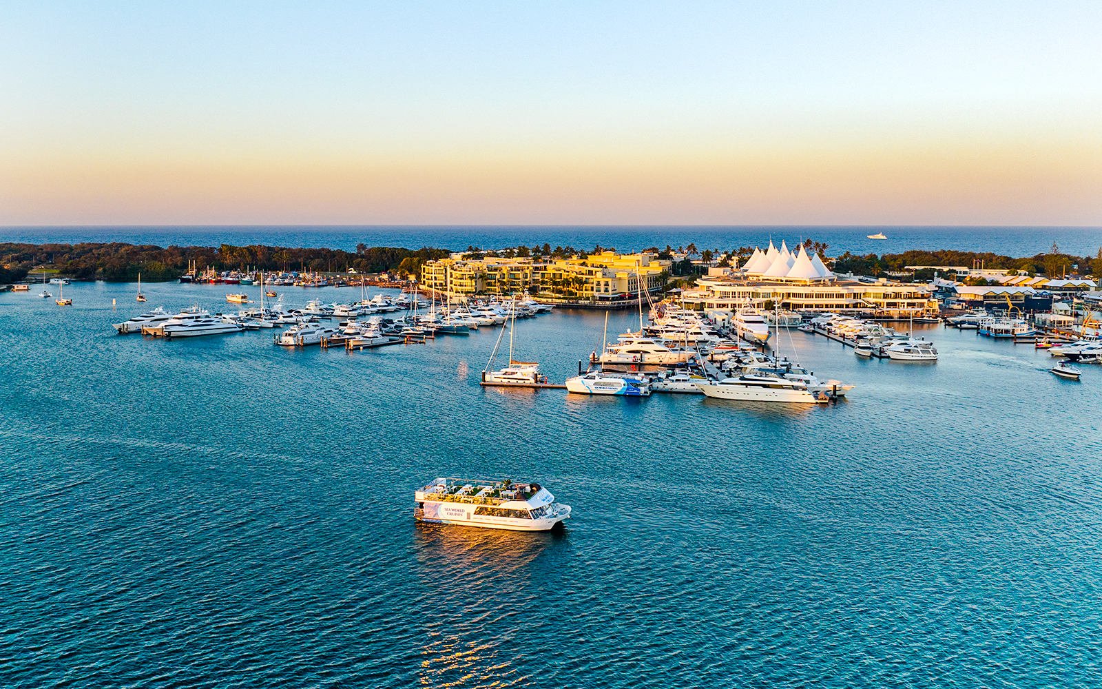 Cruise boat on Gold Coast waterway near marina at sunset.