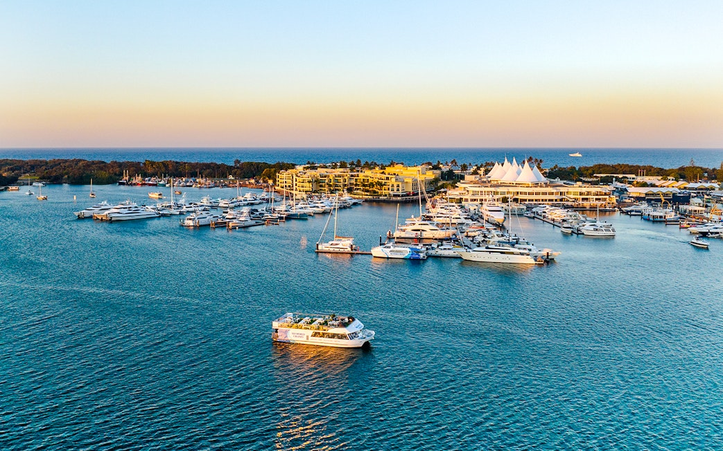 Cruise boat on Gold Coast waterway near marina at sunset.
