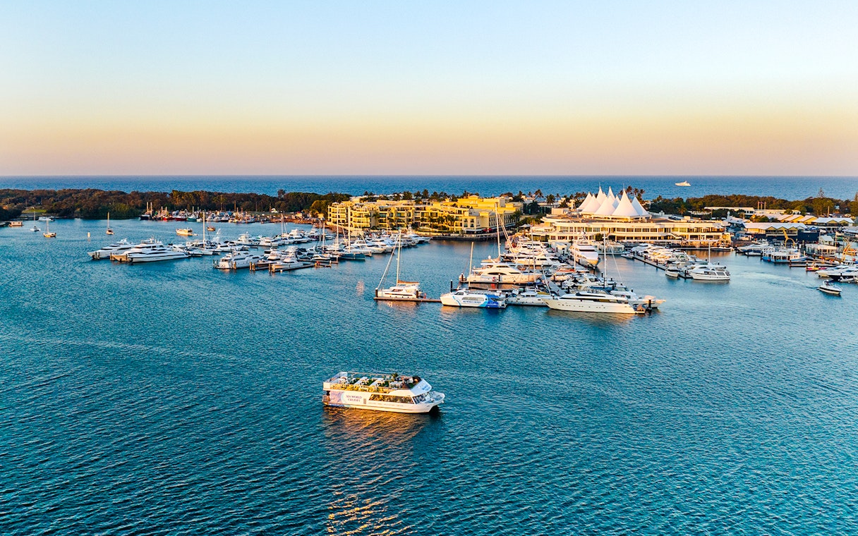 Cruise boat on Gold Coast waterway near marina at sunset.