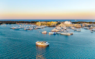 Cruise boat on Gold Coast waterway near marina at sunset.