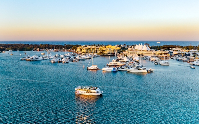 Cruise boat on Gold Coast waterway near marina at sunset.