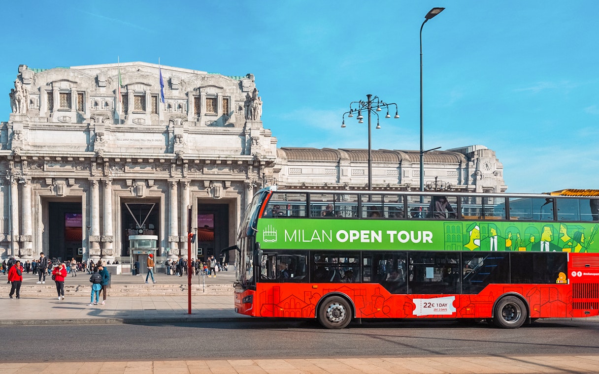 Hop-on hop-off bus in front of Milan Central Station during city tour.