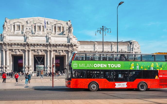 Hop-on hop-off bus in front of Milan Central Station during city tour.