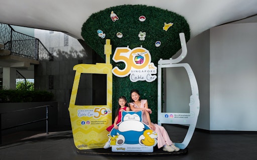 Family posing at Singapore Cable Car 50th Anniversary display with cartoon characters.