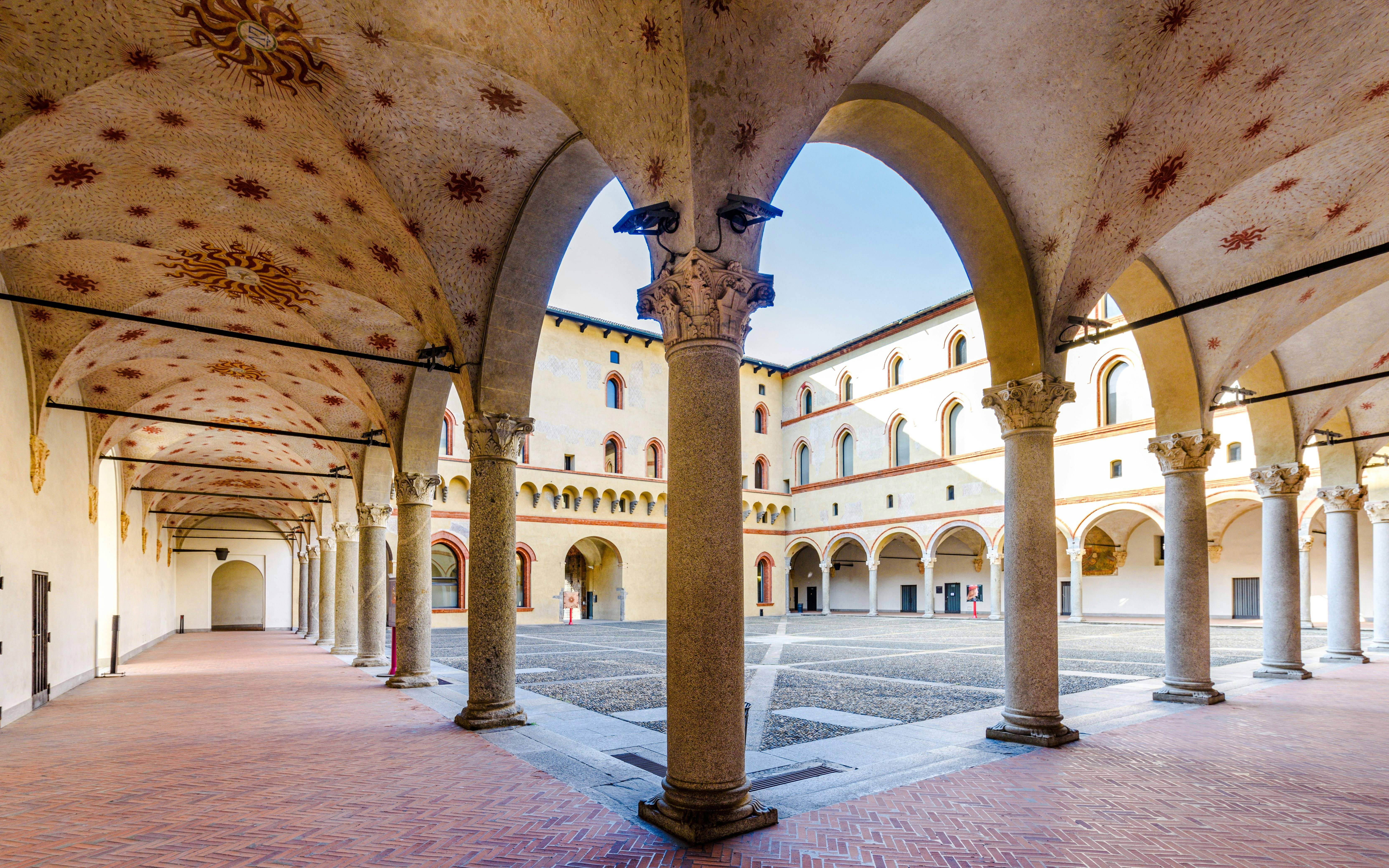 Sforza Castle courtyard with arched columns and decorative ceilings in Milan, Italy.