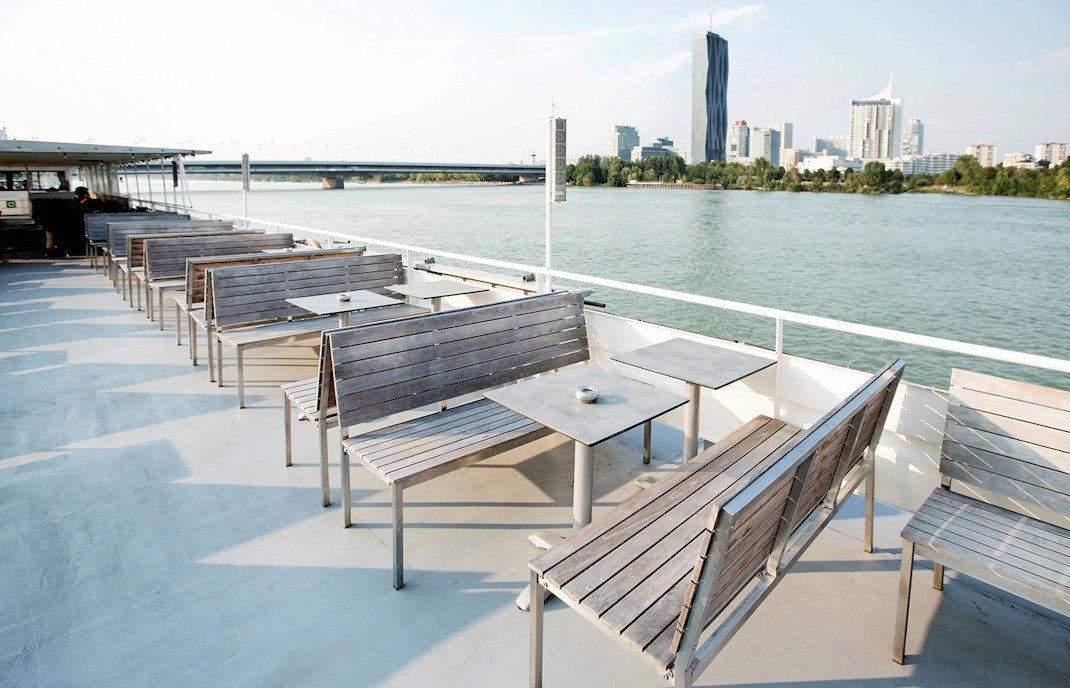Leere Holzbänke und Tische mit Aschenbecher auf dem Deck eines Schiffs